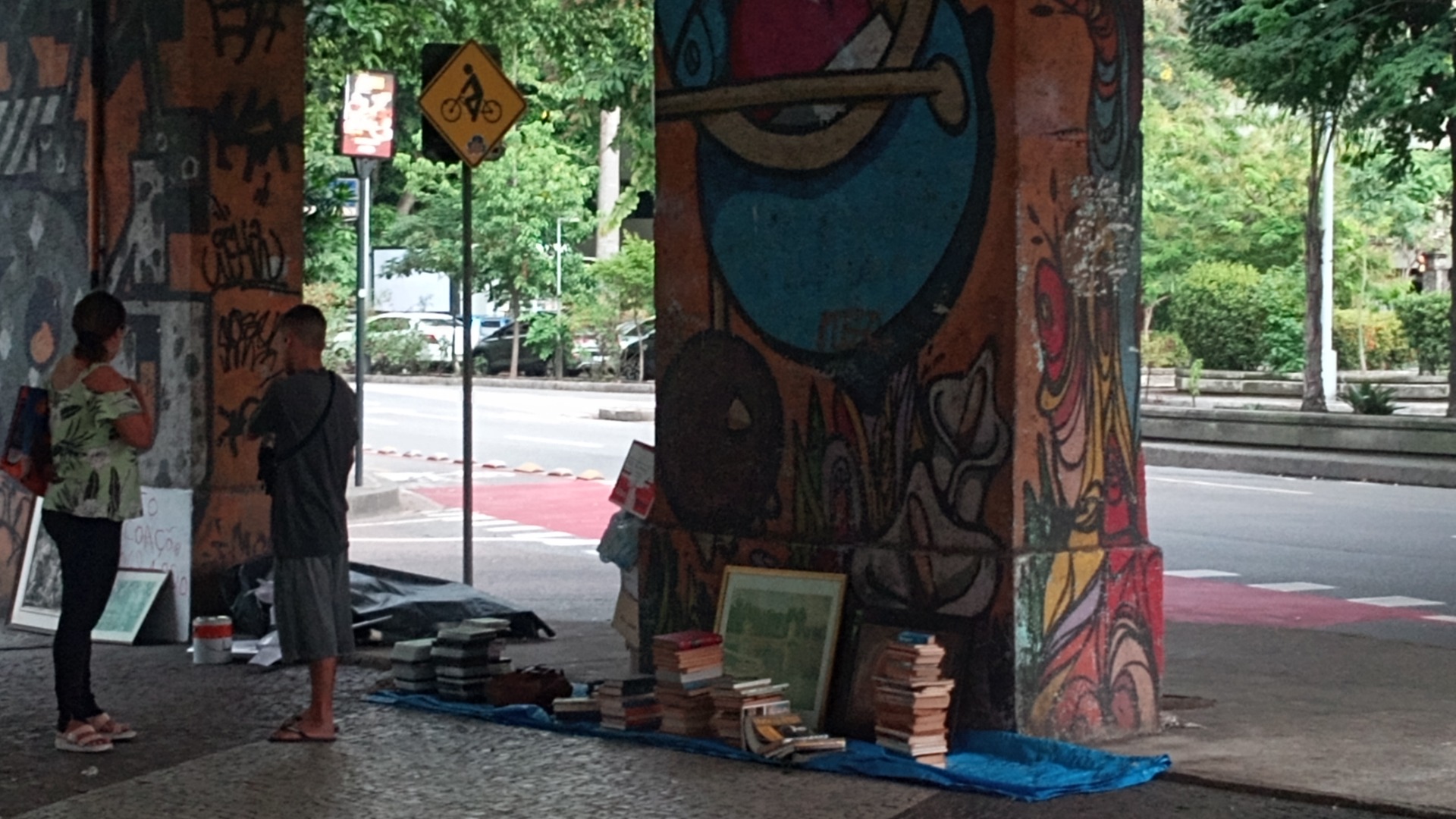 Under an overpass in town. Both of these were passers-by. There's a can for the money, but no keeper of the items. Maybe gone on a toilet call!